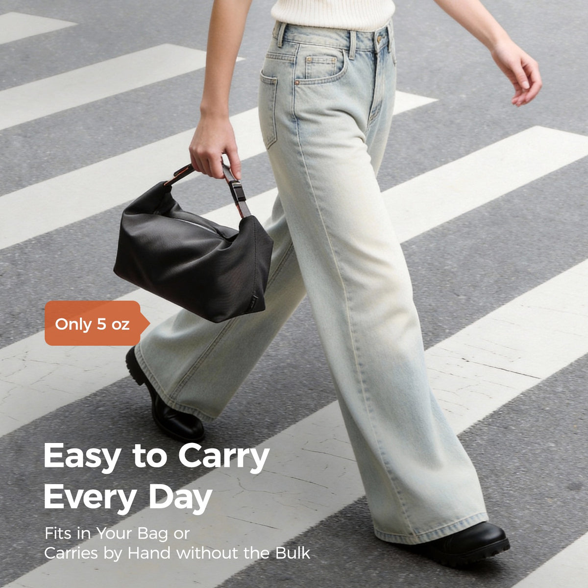 Person walking across a crosswalk while carrying the pack all® insulated lunch bag by its handle, with a label stating the bag weighs only 5 oz.